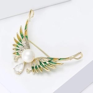 Detail of luxury angel wing brooch with white pearl, green enamel, and zircon drop