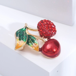 Broche cerise scintillante avec cristaux rouges et feuille émaillée verte sur base dorée