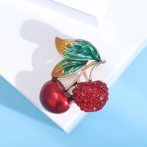 Détail de la broche cerise avec une perle en émail rouge et une cerise en strass rouge