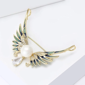 Macro detail of enamel angel wing brooch with white pearl and pear-cut zircon stone