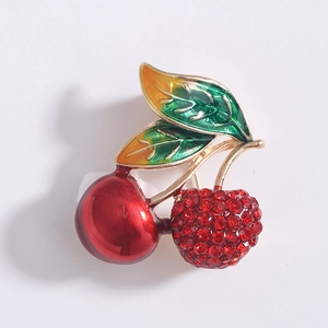 Vue détaillée de la broche cerise avec émail rouge et strass en cristal scintillants