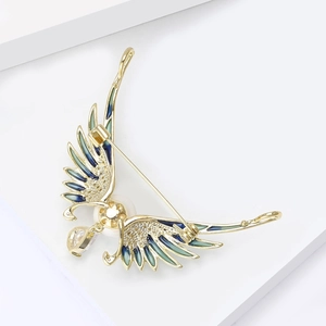 Detailed view of angel wing brooch with blue-green enamel, pearl and zircon stone