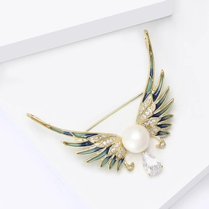 Macro detail of enamel angel wing brooch with central pearl and zircon accents