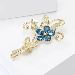 Broche bouquet élégante avec cristaux bleus et zircons sur présentoir blanc moderne
