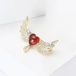Detail showing red heart brooch with crystal wings and a dangling teardrop pendant