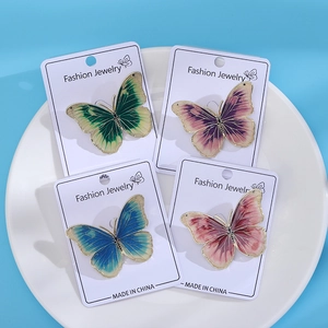 Detailed macro view of four colorful enamel butterfly brooches on a white ceramic plate