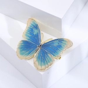 Elegant gold butterfly brooch with blue enamel gradient wings on white display