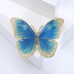 Macro shot of blue enamel butterfly brooch with gold edges on white geometric background