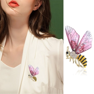 Broche abeille tendance avec ailes roses et strass scintillants sur une veste blanche