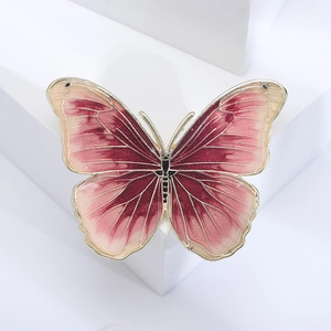 Macro detail of enamel butterfly brooch featuring red gradient wings and golden edges