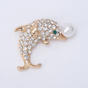 Détail d'une broche dauphin avec cristaux scintillants, oeil vert et une perle blanche