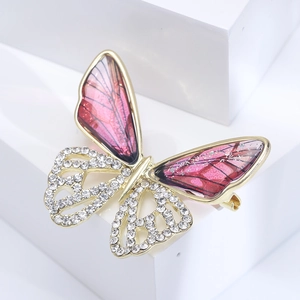 Macro shot of gold butterfly brooch featuring pink gradient wings and crystal pavé details