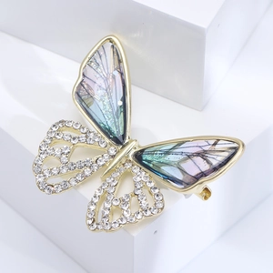 Macro shot of gold butterfly brooch with hollow crystal wings and blue gradient inlay
