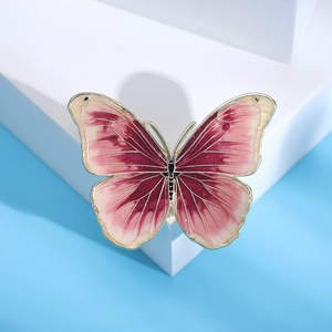 Macro detail of enamel butterfly brooch with pink gradient and elegant golden outline