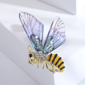 Détail de la broche abeille avec ailes violettes et strass brillants sur métal doré