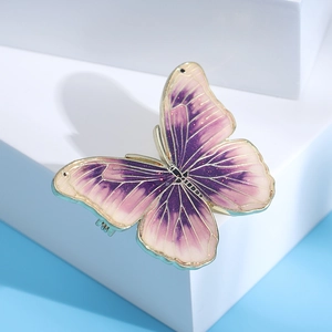Detailed macro view of gradient purple enamel butterfly brooch with gold frame and glitter