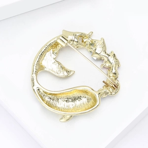 Elegant gold whale tail brooch with hammered metal texture on white platform