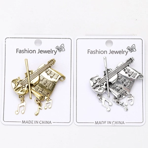 Detail view of gold and silver violin brooches with music note pendants on cards