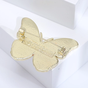 Detail view showing the golden butterfly brooch back mechanism and matte metal texture