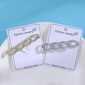 Detail view of gold and silver chunky chain brooches on a white fashion jewelry card
