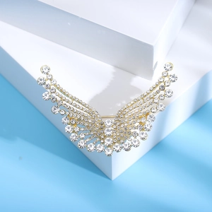 Détail de la broche ailes avec strass blancs sur base dorée et fond bleu clair