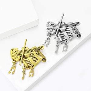 Vintage gold and silver musical instrument brooches with violin and music sheet on white cubes