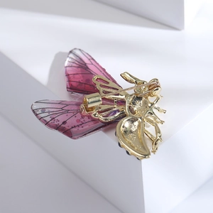 Vue détaillée du dos de la broche papillon dorée montrant l'épingle de sûreté et les ailes en résine