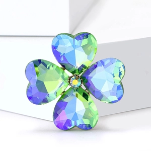 Macro shot of iridescent crystal four-leaf clover brooch with rainbow gradient finish