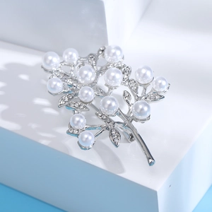 Detailed view of elegant silver brooch featuring white pearls and sparkling leaf rhinestones