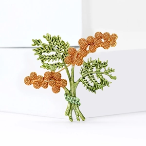 Elegant gold flower plant brooch with green enamel leaves on minimalist white blocks