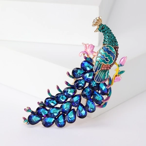 Elegant peacock brooch with blue crystal tail and enamel details on a gold base