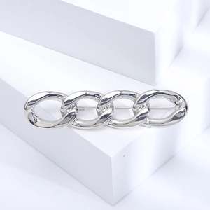 Detailed view of polished silver chain link brooch on a white geometric platform