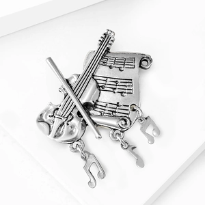 Detailed view of vintage silver music brooch with violin, scroll, and dangling notes