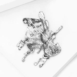 Macro detail of vintage musical brooch back showing metal texture and safety pin clasp