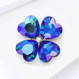 Macro view of four-leaf clover brooch with blue heart-shaped crystal petals and gold base