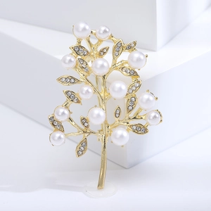 Detailed macro shot of golden alloy tree brooch with white pearls and sparkling rhinestones
