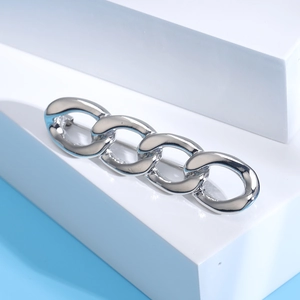 Detailed close-up of a silver chain-link brooch with a polished finish and pin clasp