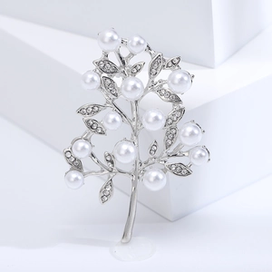 Macro view of tree-shaped brooch with silver branches, inlaid pearls and sparkling crystals