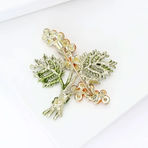 Minimalist plant brooch with green enamel details and long pin fastening for suits