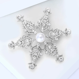 Vue détaillée d'une broche flocon d'argent avec strass brillants et perle centrale