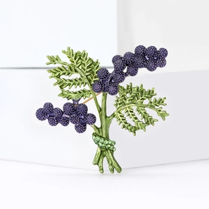 Minimalist plant brooch featuring purple berries and green leaves with crystal accents