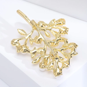 Macro view showing back pin detail and golden vine structure of the pearl brooch