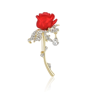 Elegant red rose brooch with gold alloy stem and sparkling crystals in a white background