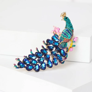 Exquisite peacock brooch with blue crystals and enamel on a minimalist white stand
