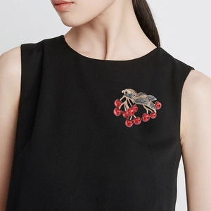 Elegant cherry brooch with red beads and black gold leaves on a black blouse