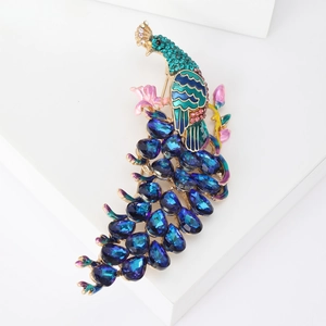 Vintage gold peacock brooch with blue crystals and green enamel on white display