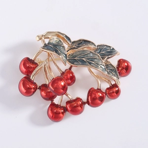Detailed close-up of cherry brooch with red glossy fruits and green enamel gold leaves
