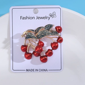 Detailed close-up of cherry brooch with red enamel berries and green alloy leaves