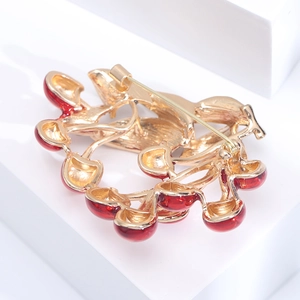 Detailed back view of gold-plated cherry brooch with red enamel and safety pin closure
