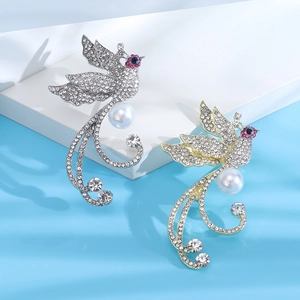 Détail de broches phénix de luxe avec cristaux pavés et perles blanches sur fond bleu